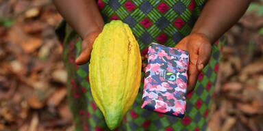 3x2-Dora Atiiga, Kakaobäuerin aus Ghana zeigt Kakaoschote und Schokolade-©Fairtrade-Nipah-Dennis.jpg
