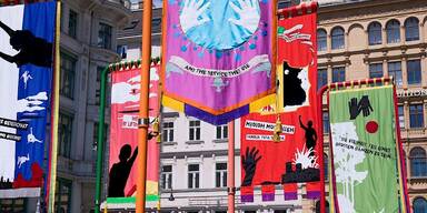 Freiluft-Ausstellung zeigt bunte Flaggen am Graben